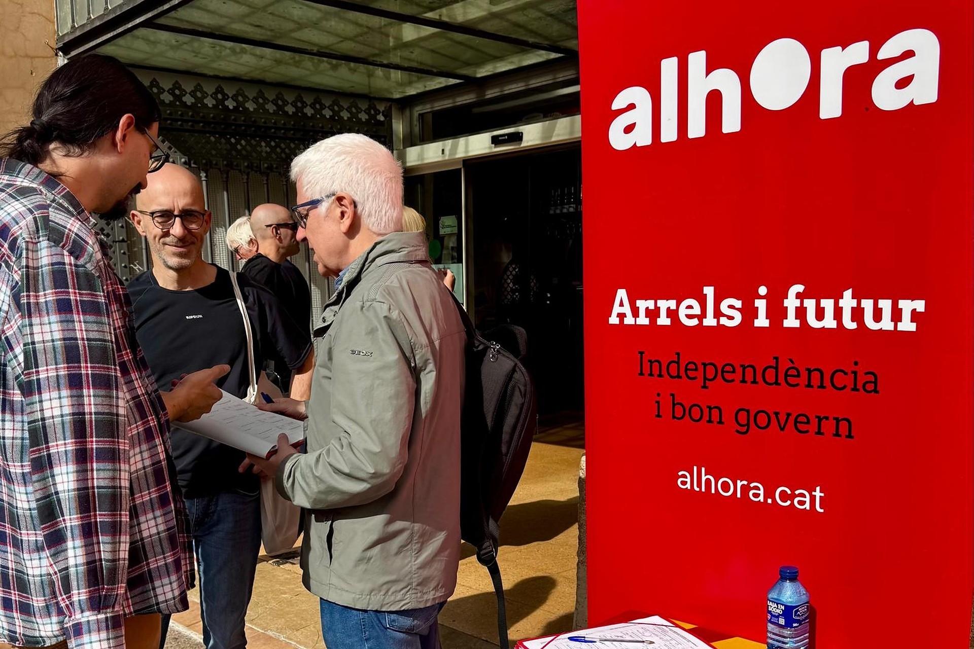 Una parada de recollida de signatures d’Alhora, amb el cartell «Arrels i futur»
